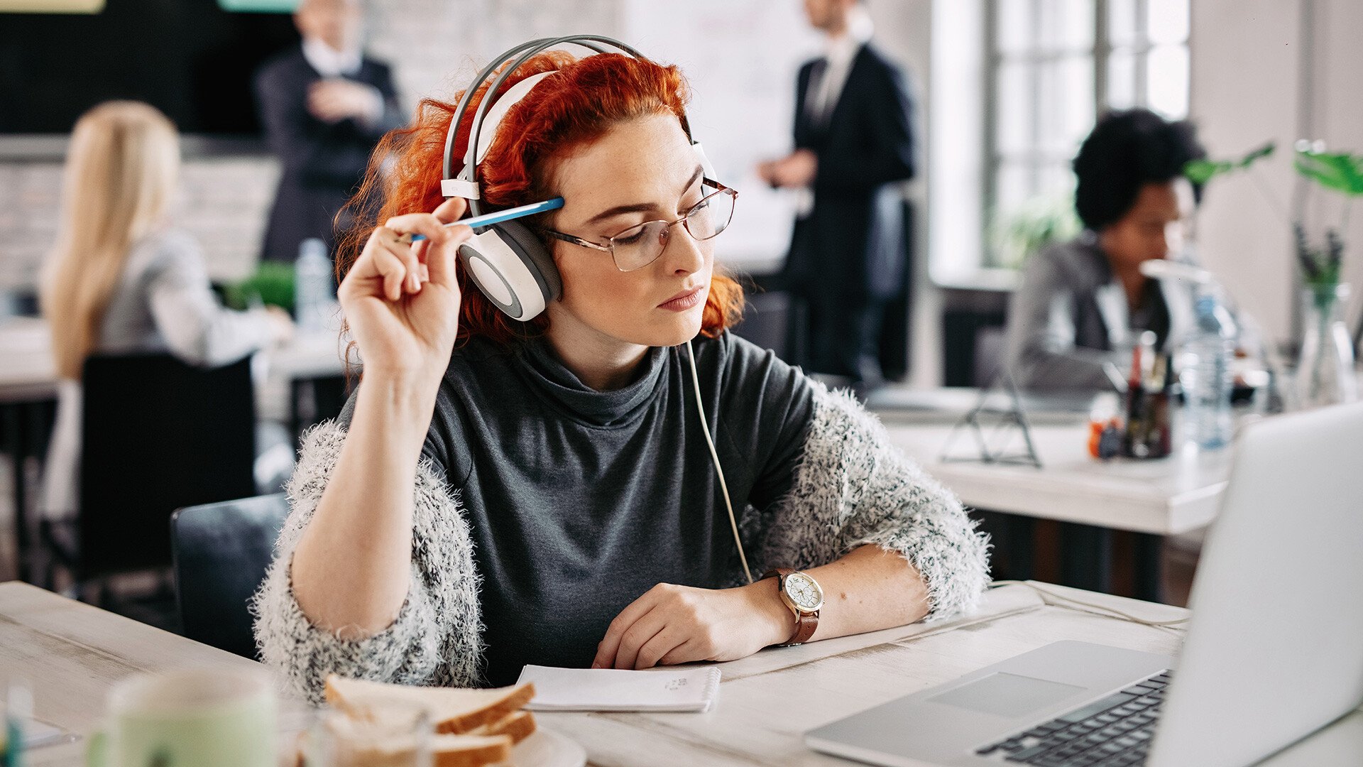 En person med hörlurar som sitter framför datorn | Bach eller Britney välj rätt spellista på jobbet - Seiva.