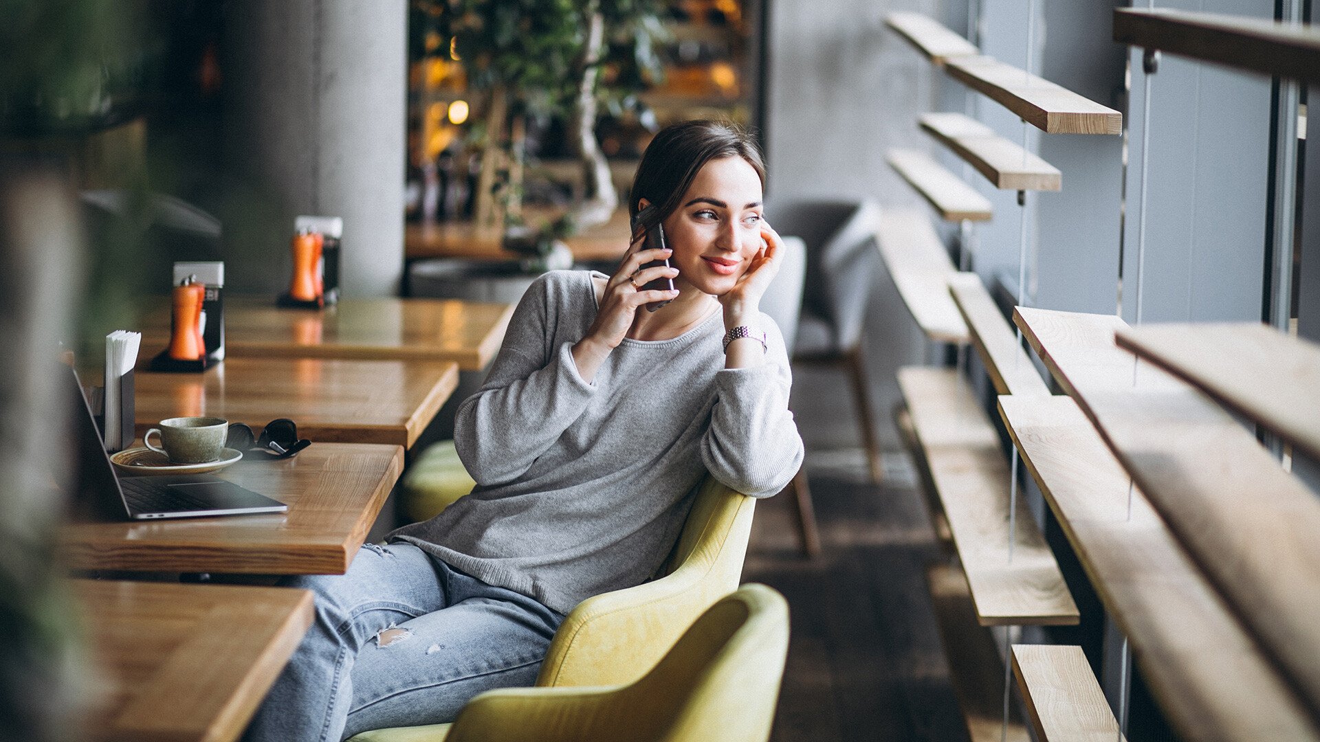 En person på ett café som pratar i telefon | Din arbetsmiljöpolicy är en vinstgenerator - Seiva.