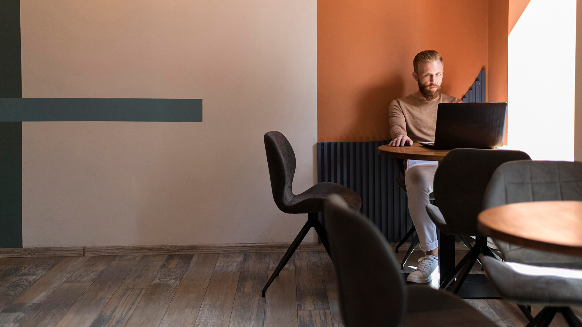 En person som sitter i en sittgrupp med sin laptop - Säg det i din personalhandbok | Seiva.