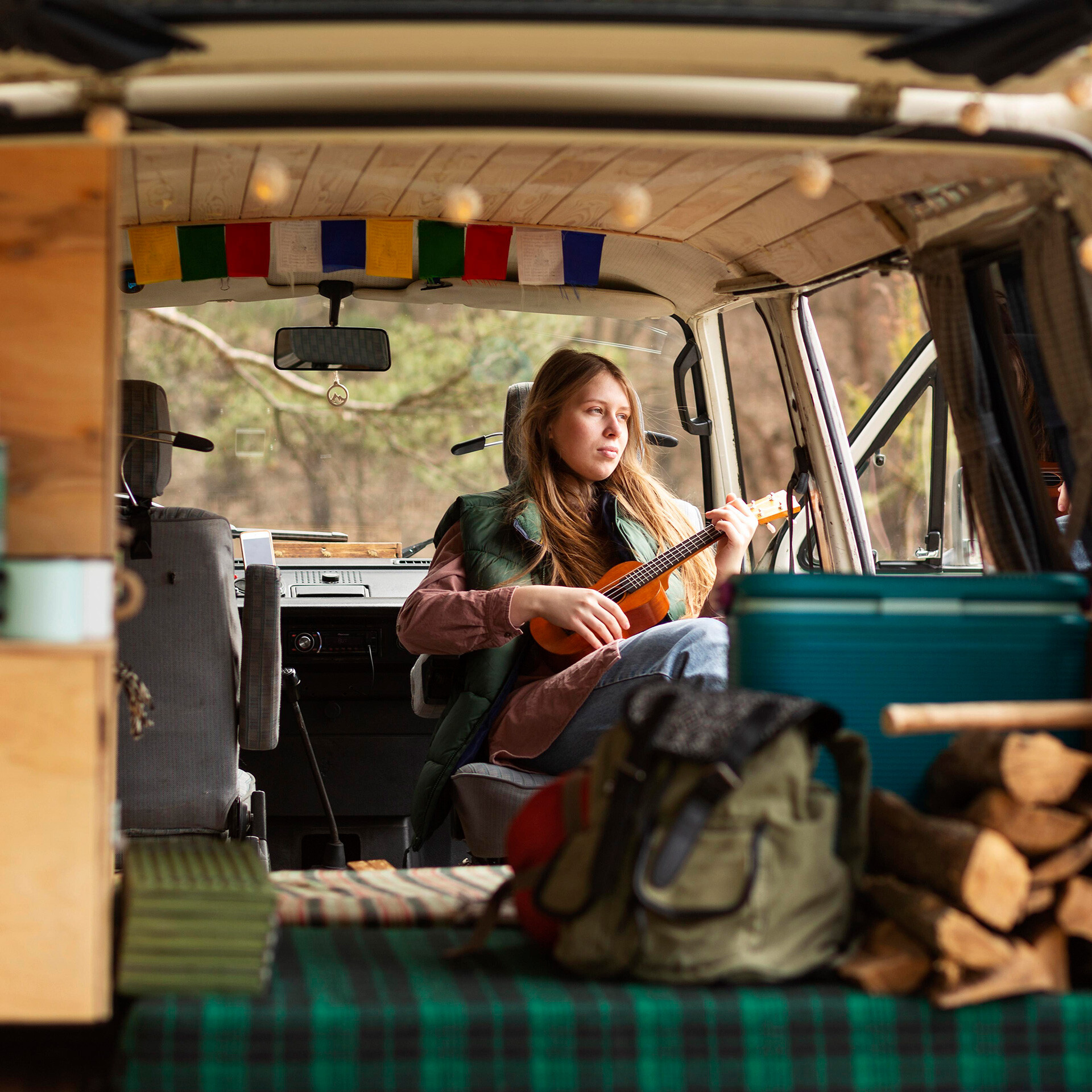 Person sitter i en minivan och spelar på en mindre gitarr.